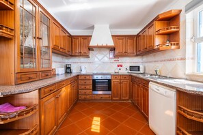 Una cocina con armarios de madera, horno empotrado, lavavajillas y microondas.