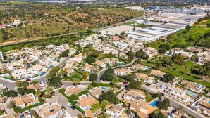 Un quartier résidentiel avec des maisons, des rues et, au loin, un grand complexe industriel.