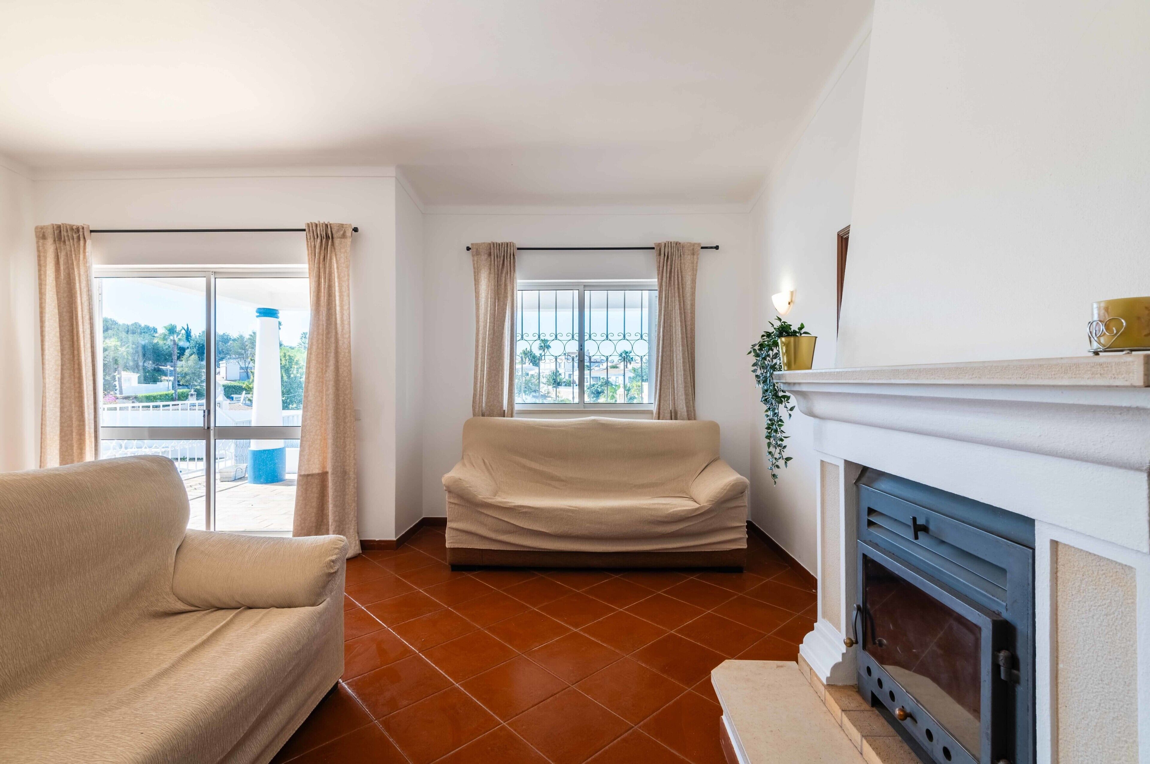 Ein Wohnzimmer mit einer Couch, einem Kamin und Blick durch ein Fenster.