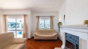 Un salon avec un canapé, une cheminée et une vue par la fenêtre.