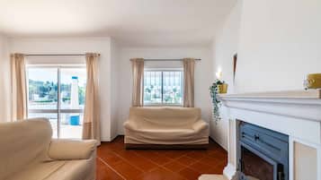 Ein Wohnzimmer mit einer Couch, einem Kamin und Blick durch ein Fenster.