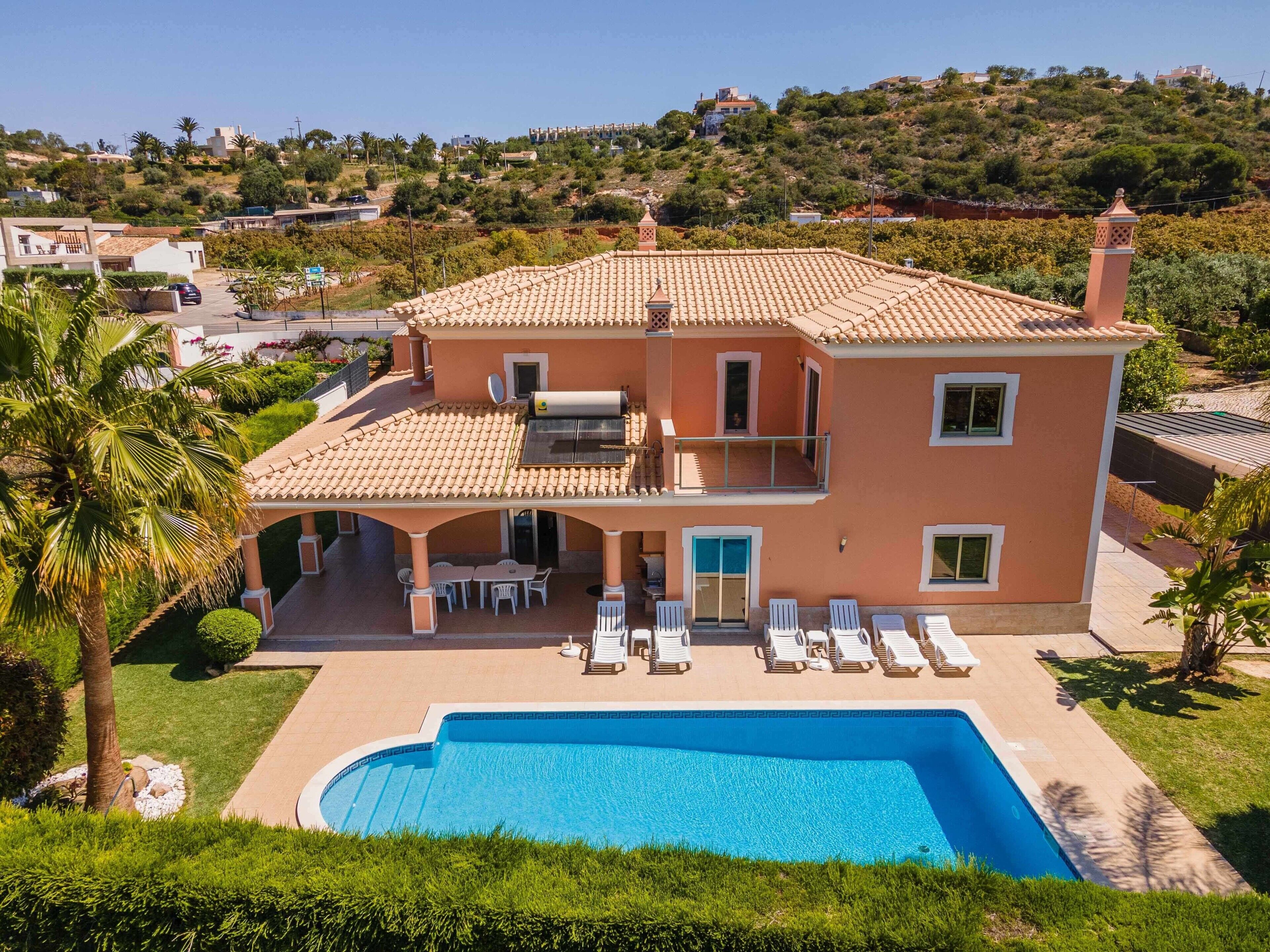 Una casa de dos pisos con piscina, un porche cubierto y vistas a un paisaje montañoso.