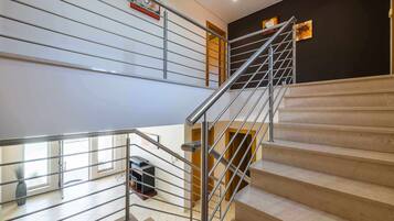 Una escalera moderna con barandillas metálicas, acabado de madera y vista al nivel inferior.