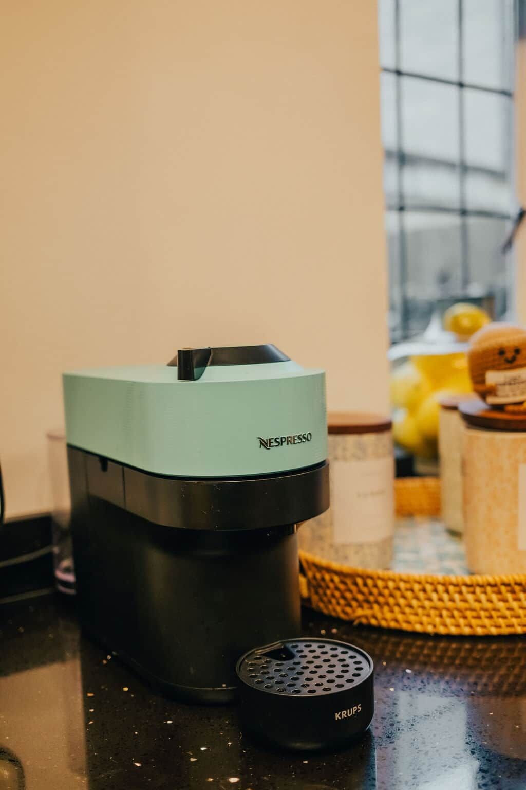 Una máquina de café Nespresso con un dispensador de cápsulas Krups sobre una encimera de cocina.