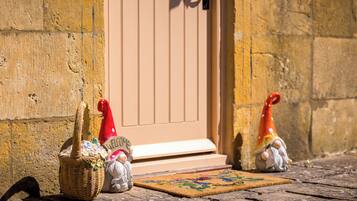 Una cesta de mimbre, un felpudo y dos figuritas de gnomos frente a una puerta.