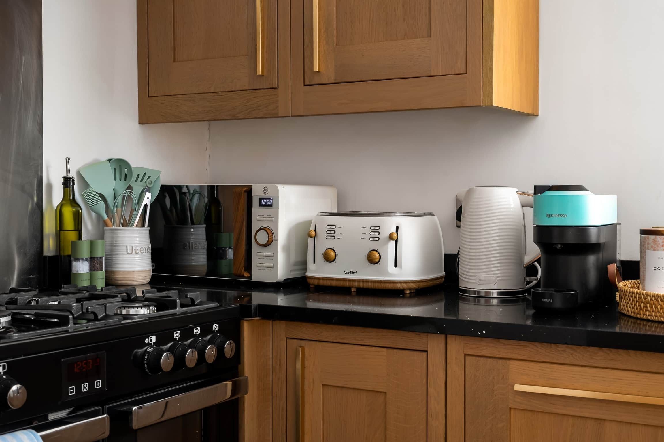 A kitchen with a stove, toaster, coffee maker, and cabinets.