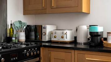 A kitchen with a stove, toaster, coffee maker, and cabinets.