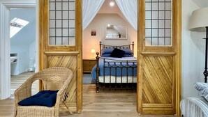 A bedroom with a bed, a wicker chair, and a nightstand. - Apple Tree Barn by inspirestays.com - a cottage that sleeps 4 guests in 2 bedrooms (Walberton Green, nr Arundel)