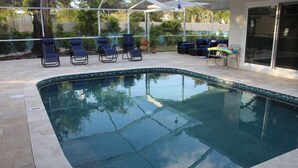 Une piscine avec des chaises longues et un espace patio couvert.