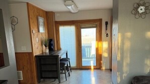 Un salon moderne avec un plancher en bois, un canapé foncé et un coin repas comprenant une table et des chaises.