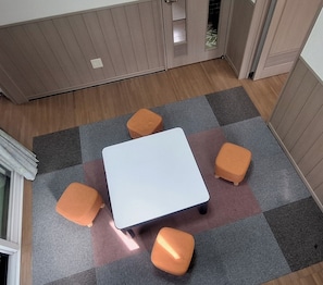 Cozy space with a central table and four cushioned stools, set against a checkered floor and light wood paneling.