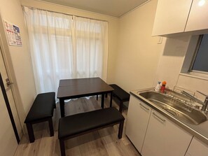 A compact kitchen with a dining table, bench, and a built-in sink.