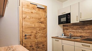 A kitchen with wooden cabinetry, a microwave, a sink, and a wooden table.
