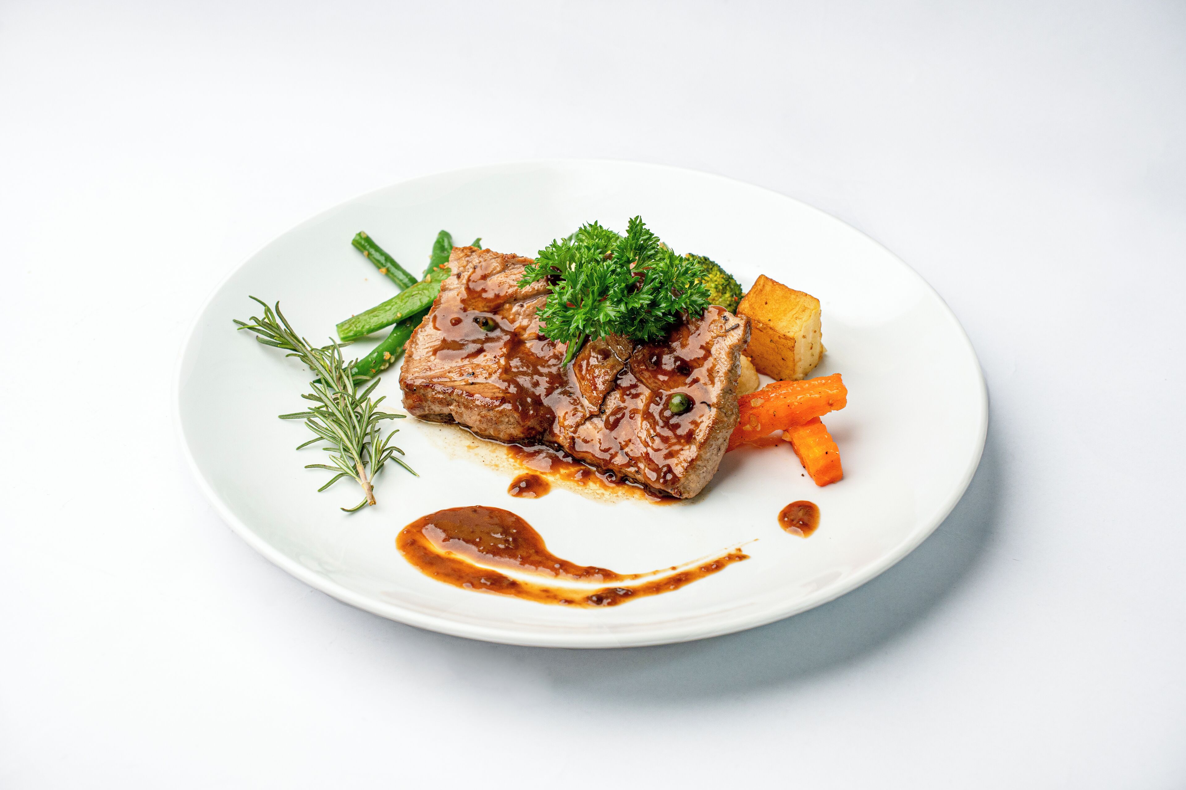 A plate of food with a piece of meat, vegetables, and a garnish.