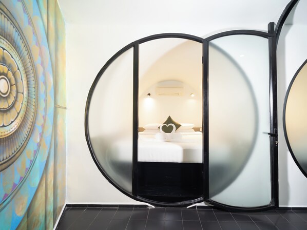 A room with a bed, a heart-shaped decoration, and a circular mirror. - Tunnel Urban Retreat (Siem Reap)