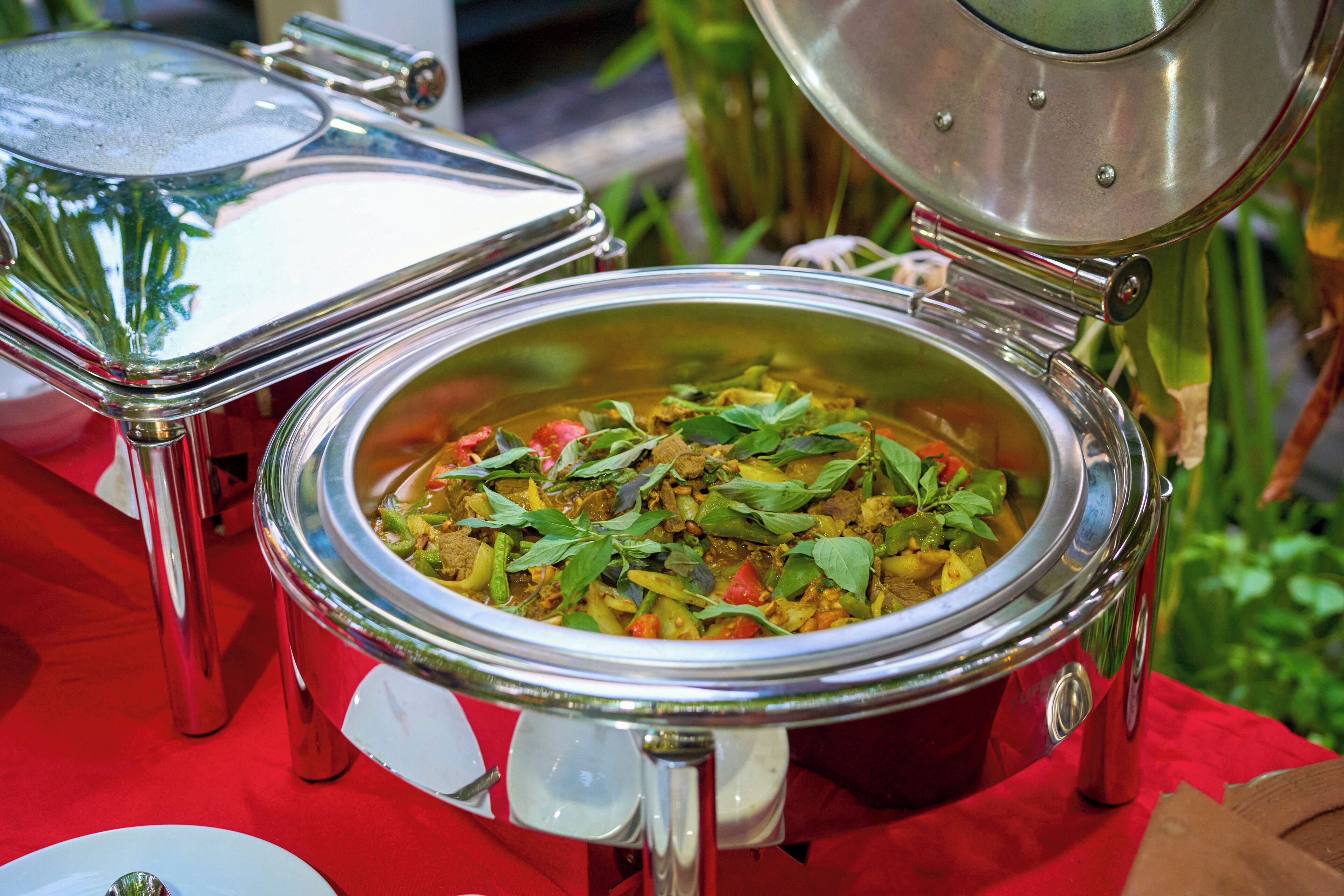 A food container with a lid, placed on a table with a red tablecloth.