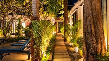 A pathway lined with trees and plants leading to a building with a modern design.
