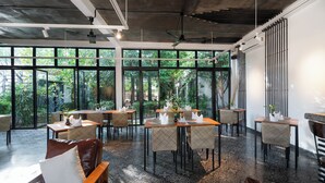 A modern restaurant with large windows, indoor plants, and a patterned floor. - Tunnel Urban Retreat (Siem Reap)