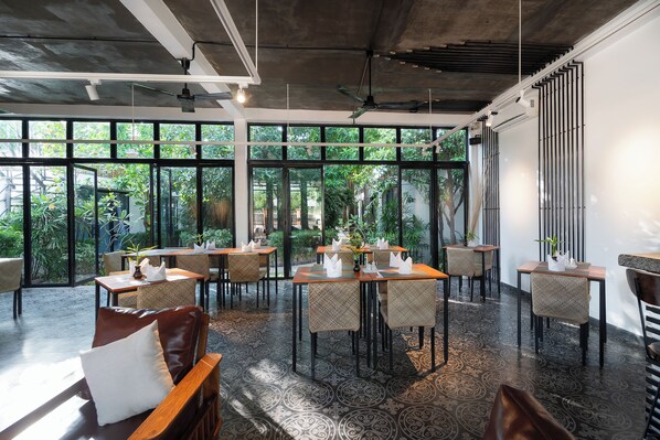 Un restaurant moderne doté de grandes fenêtres, de plantes d’intérieur et d’un sol à motifs.