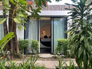Un bâtiment moderne avec une porte vitrée donnant sur une chambre à coucher équipée d’un lit et d’une table de chevet.