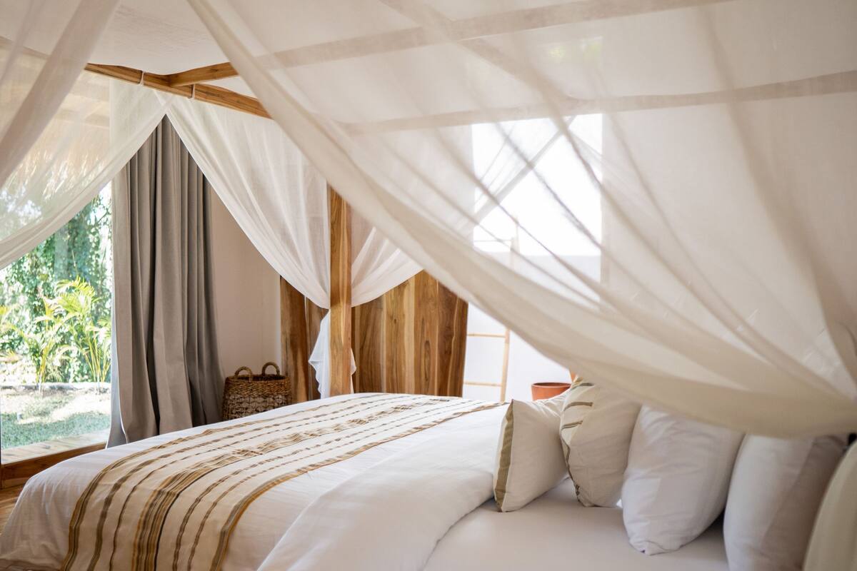 Un dormitorio con una cama grande, ropa de cama blanca y dosel.