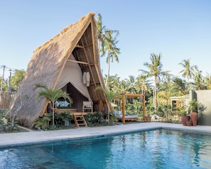 Una edificación con techo de paja y una piscina delantera.