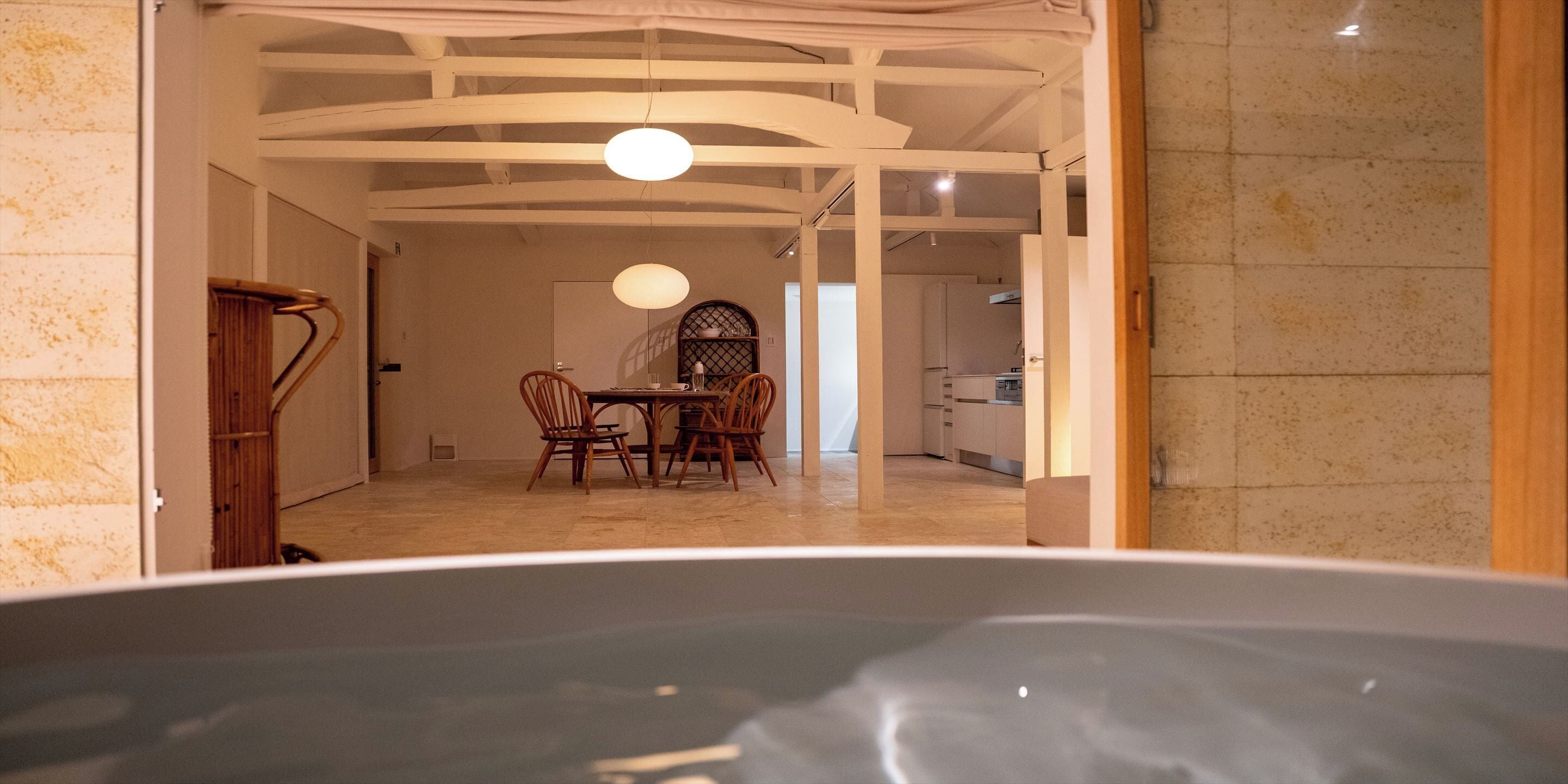 A modern interior with a dining area, kitchen, and a large bathtub.