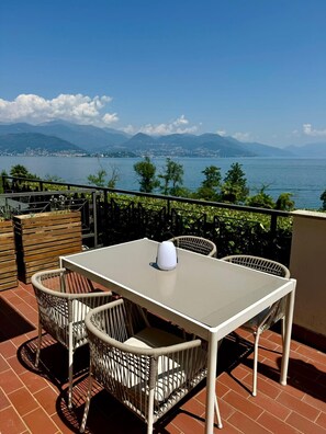 En terrasse med et bord og stole, med udsigt over en sø og bjerge.