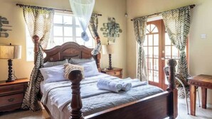 Une chambre à coucher avec un lit en bois, des rideaux, une table de chevet et une moustiquaire suspendue.