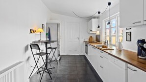 Une cuisine moderne avec des meubles blancs, un plan de travail en bois et une chaise noire.