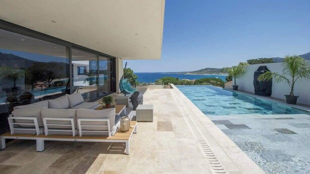 Un espacio al aire libre moderno con piscina, asientos y vistas al mar.