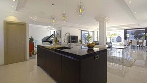 Una cocina moderna con una isla central, luces colgantes y vistas al área de comedor.