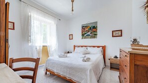 Un dormitorio con una cama y cómoda de madera, una silla y una mesita de noche.