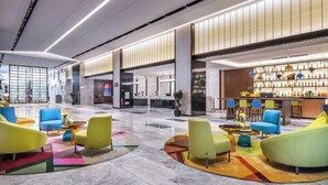 Un'ampia hall con posti a sedere moderni, un'area bar e un soffitto ben illuminato.