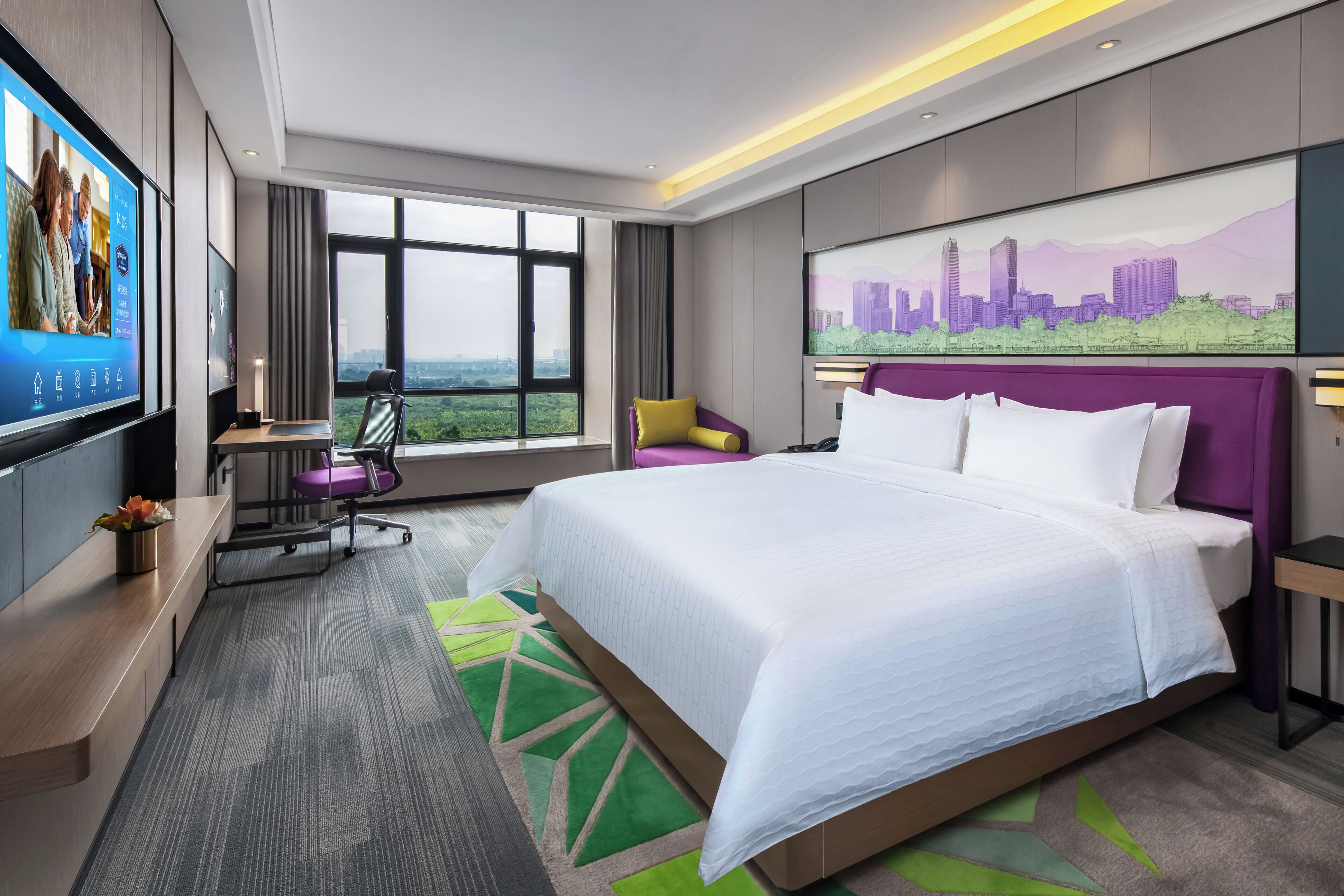 A modern hotel room with a large bed, a desk with a computer, a TV, and a cityscape painting on the wall.