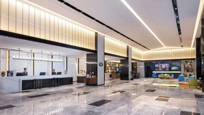 Una hall d'albergo moderna con una reception, una zona salotto e un bar.