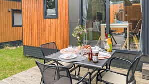 Un espace extérieur aménagé pour prendre les repas, avec une table dressée pour deux personnes, entourée de chaises.