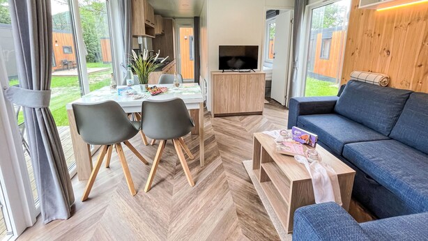 Un salon moderne comprenant un canapé, une table à manger avec des chaises, un téléviseur et un coin cuisine.