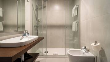 Un baño moderno con ducha envuelta en vidrio, lavamanos, un bidé y un inodoro.