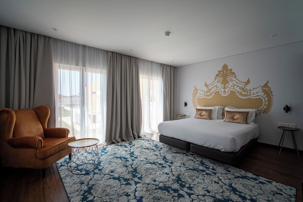 A hotel room with a bed, a chair, a small table, and a patterned rug. - Palácio Santa Catarina (Angra do Heroismo)