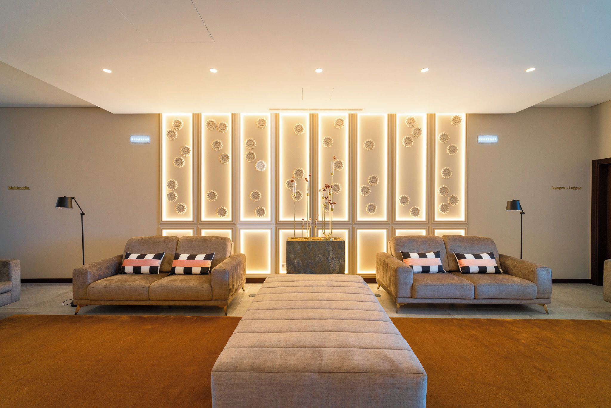 A modern living room with two sofas, a coffee table, and a decorative wall with vertical panels.