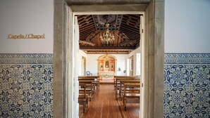 A chapel with wooden pews, a chandelier, and patterned walls. - Palácio Santa Catarina (Angra do Heroismo)