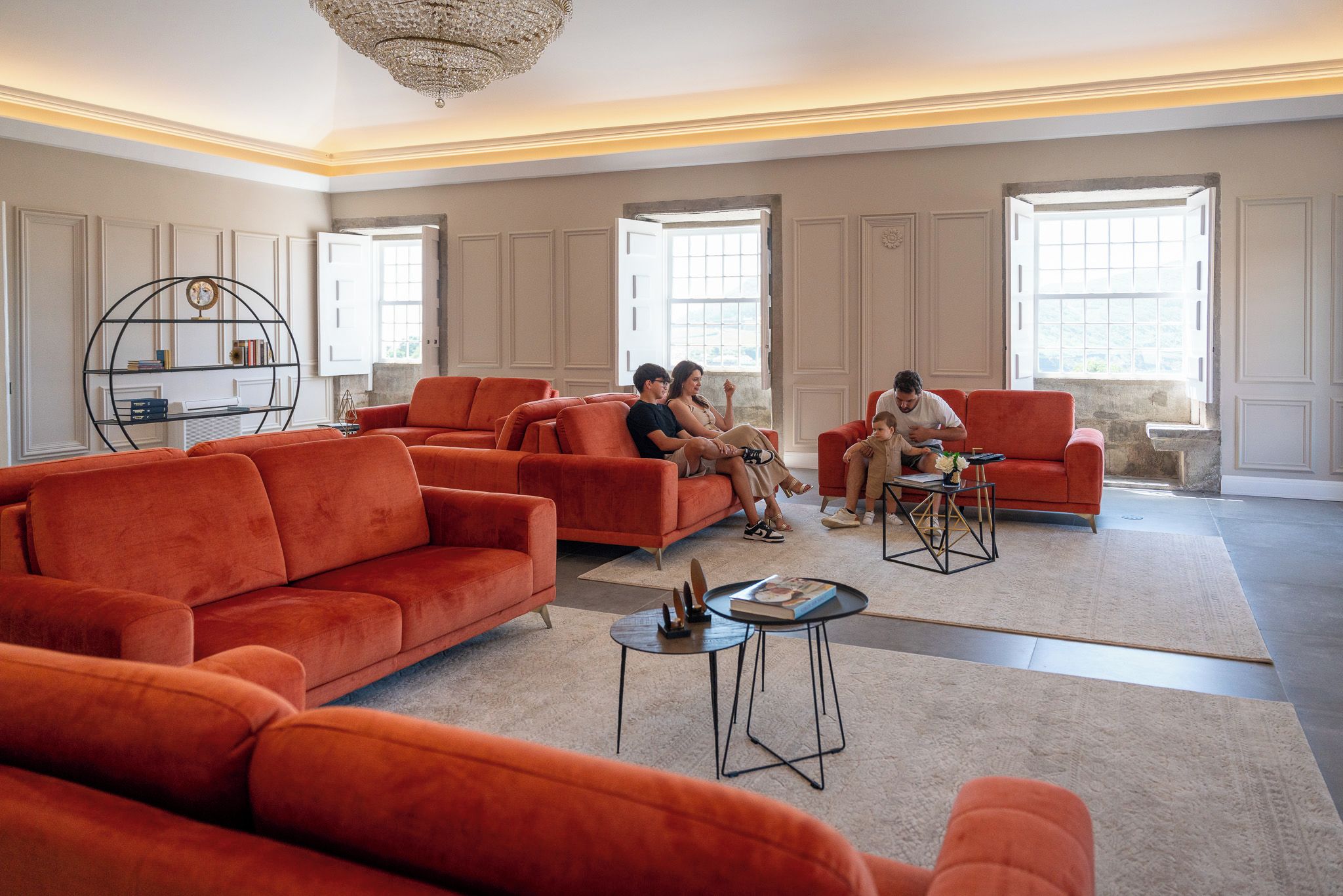 A spacious living room with a large red sofa set, a coffee table, and a bookshelf.
