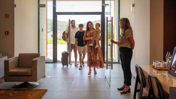 A hotel lobby with a reception desk, a seating area, and a glass door entrance.
