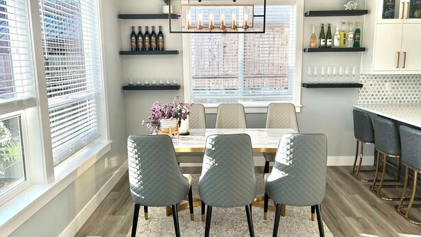 A dining area with a table, chairs, and a chandelier. There are shelves with bottles and a plant. - Charming house with Beautiful Sunset View (Dallas)