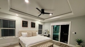A bedroom with a bed, bench, ceiling fan, and large windows. - Charming house with Beautiful Sunset View (Dallas)