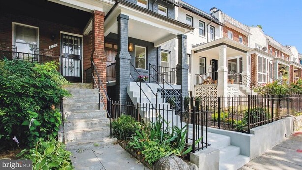 A row of townhouses with a front porch, a staircase, and a black metal fence. - Modern & Elegant One-Bedroom in NoMa, DC (Washington)