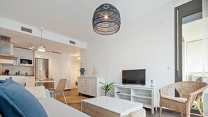 Un soggiorno moderno con un divano, una TV, un'area pranzo e una cucina.