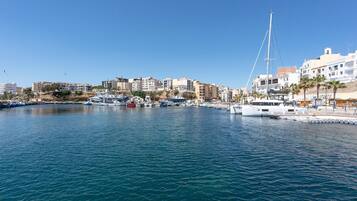 Un port esportiu amb vaixells amarrats, un pont i edificis al passeig marítim.