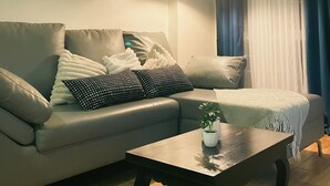 Un salon comprenant un canapé, une table basse, une lampe et un appareil de climatisation.